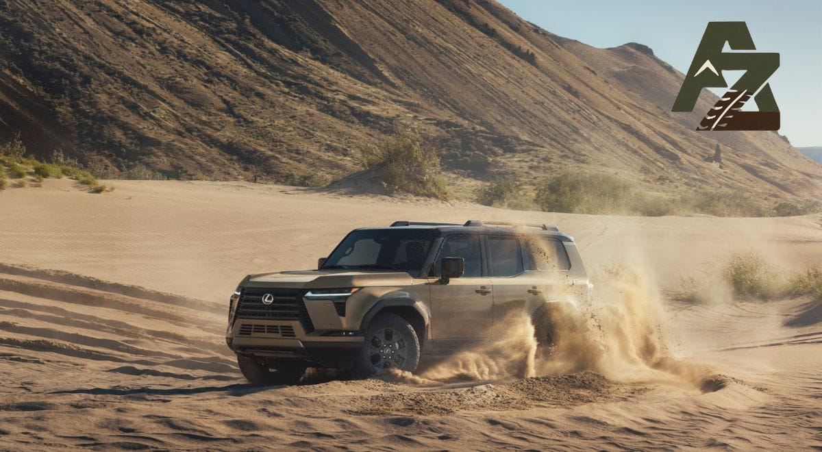 2024 Lexus GX550 driving off-road over rocky terrain, showing its squared design and adventure-ready stance.